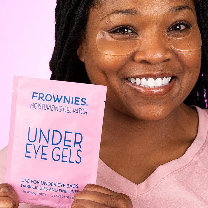 Woman holding box of Frownies Under Eye Gels smiling after use