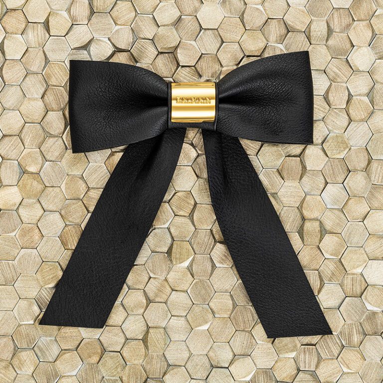 Balmain Hair Couture | Leather Barrette Bow with 18K Gold Detail against a wooden detail backdrop