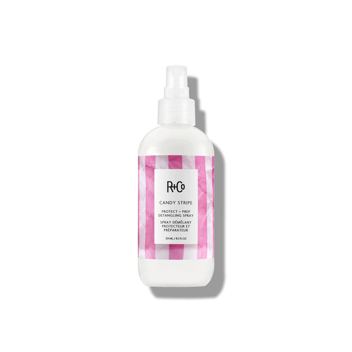 Image of CANDY STRIPE Protect + Prep Detangling Spray alongside a hairbrush and styling tools.