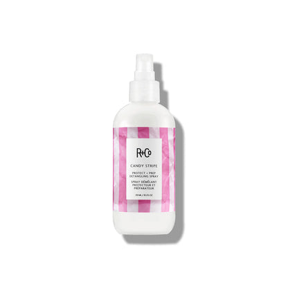 Image of CANDY STRIPE Protect + Prep Detangling Spray alongside a hairbrush and styling tools.