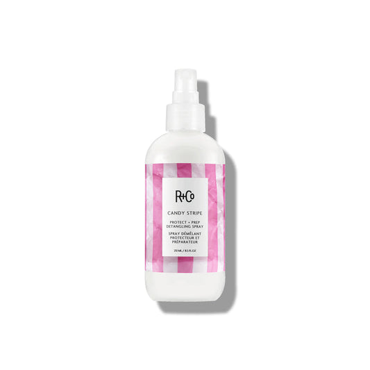 Image of CANDY STRIPE Protect + Prep Detangling Spray alongside a hairbrush and styling tools.